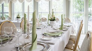 A formal dining table set with white tablecloths, green napkins, and silverware. - Dronninglund Hotel (Dronninglund)