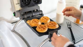 Una piastra per waffle con quattro waffle in cottura.