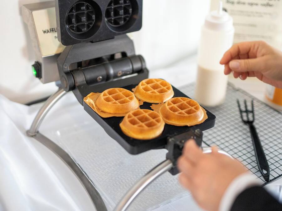 Una piastra per waffle con quattro waffle in cottura.