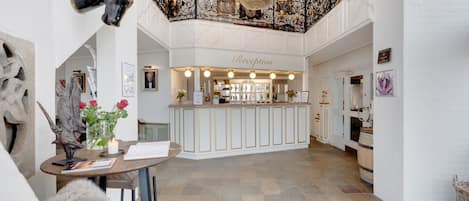 Et receptionsområde med en lysekrone, en receptionsdisk og en bar.