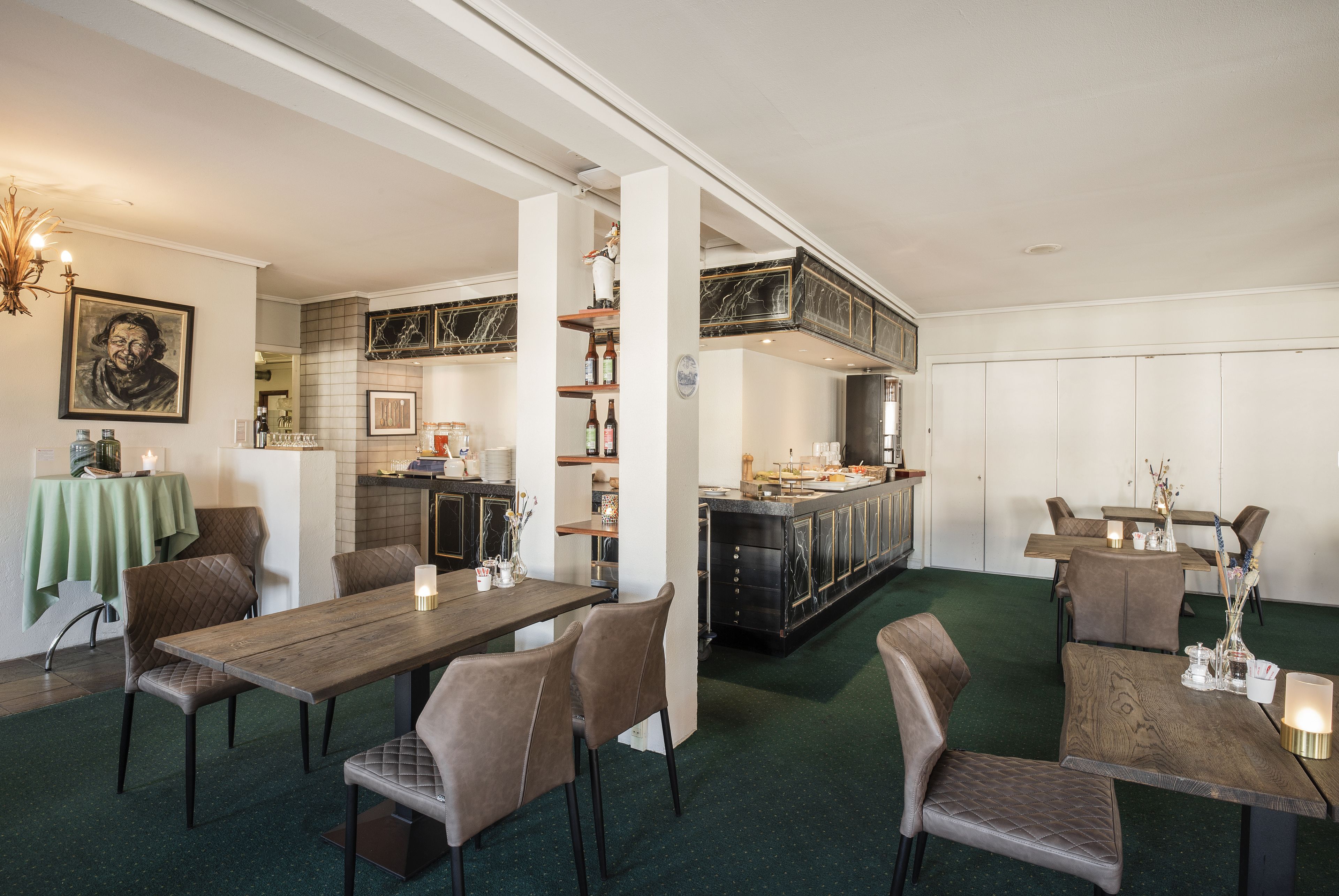 A dining area with a long wooden table, several chairs, and a kitchen in the background.