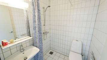 A bathroom with a shower, toilet, sink, and a mirror.