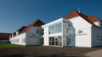 A modern hotel building with a white facade and red-tiled roofs.