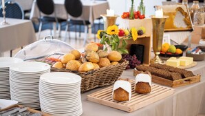 Uma mesa de buffet com diversos pães, queijos e frutas.