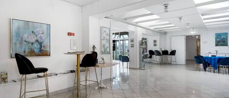 A spacious, well-lit room with a tiled floor, a round table with chairs, and artwork on the walls.