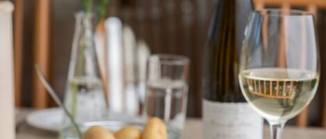 A dining table with a plate of food, a bottle of wine, and a glass of wine.