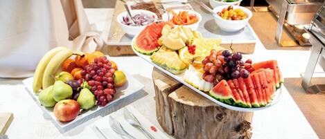 A buffet table with various fruits and vegetables, including watermelon, grapes, and pears.
