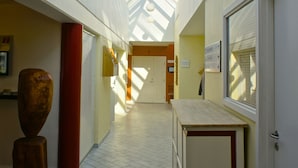 A corridor with a skylight, a wooden sculpture, and a counter with a door. - Hotel Årslev Kro (Aarhus)