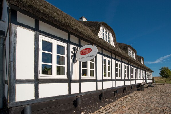 A traditional half-timbered building with a thatched roof and a sign indicating it is a 'rustike landkocken' restaurant. - Hotel Årslev Kro (Aarhus)