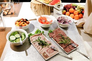 A buffet table with various food items including sliced meats, vegetables, and fruits. - Hotel Årslev Kro (Aarhus)