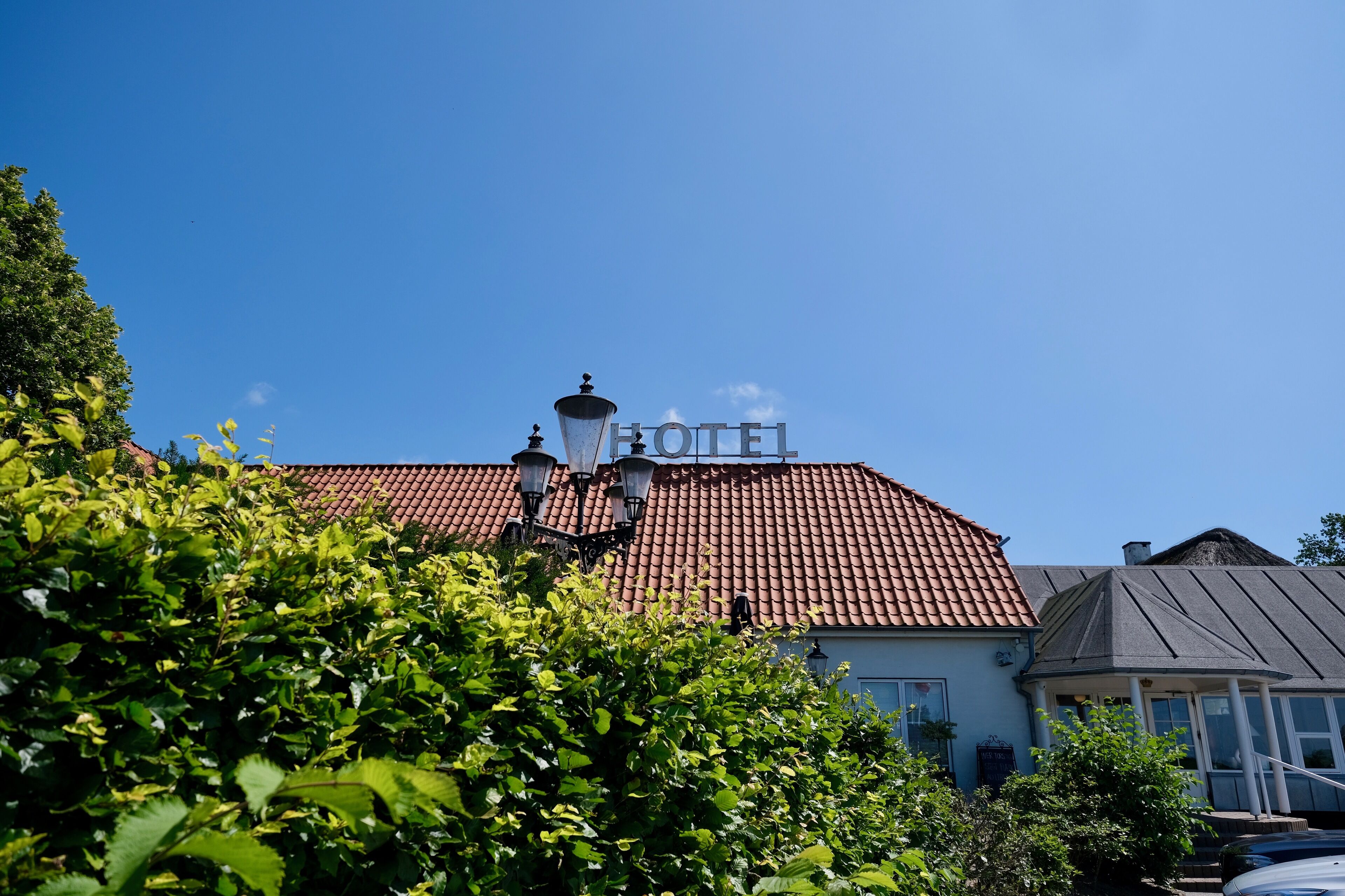 A hotel with a red-tiled roof, a sign reading "HOTEL", and a person standing on the roof.
