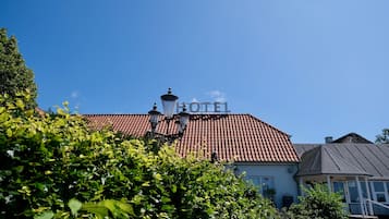 Et hotel med røde tegltagsten, et skilt med teksten "HOTEL" og en person stående på taget.