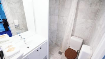 Un baño con lavamanos blanco, un espejo, cortina de ducha y un inodoro.