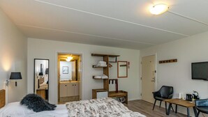 A bedroom with a bed, a wooden nightstand, a chair, a small table, a mirror, and a television. - Hotel Årslev Kro (Aarhus)