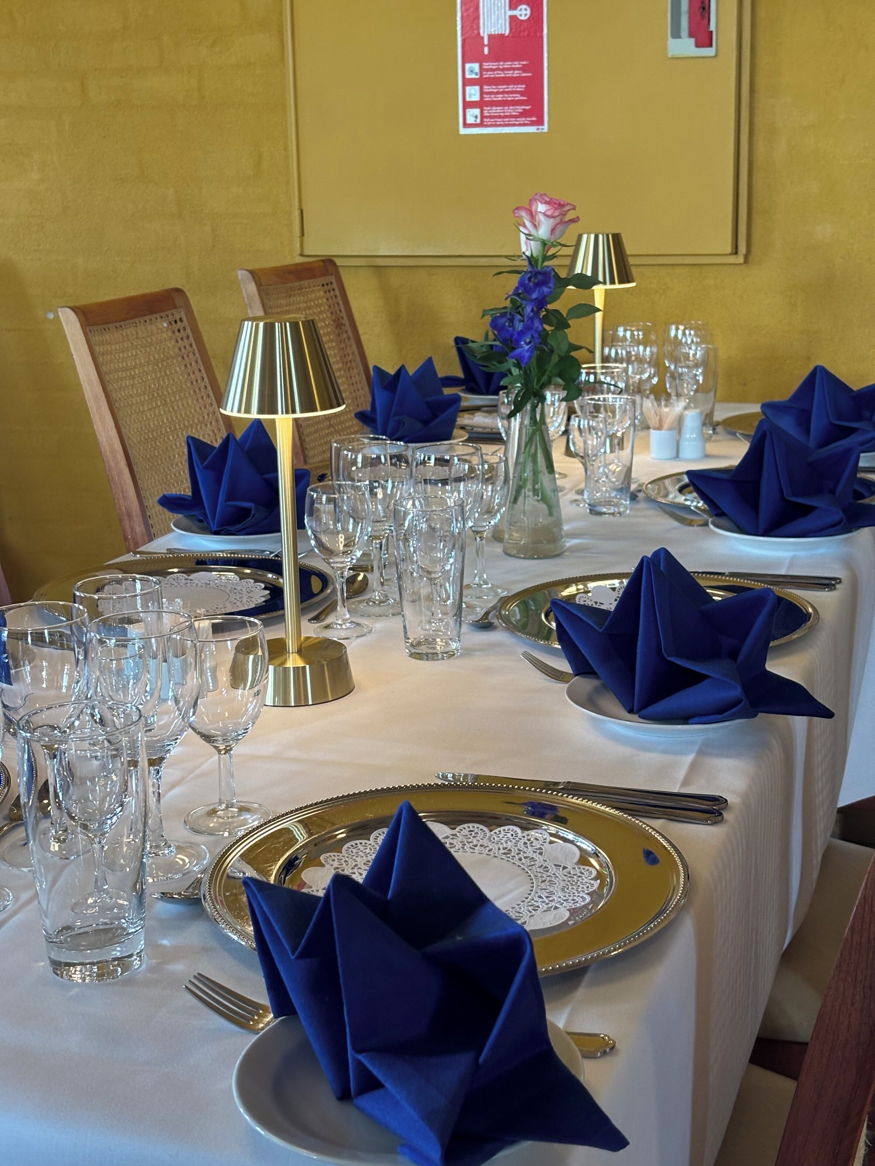 A table set for a formal dining event with multiple wine glasses, plates, and cutlery.