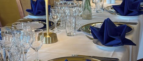 A table set for a formal dining event with multiple wine glasses, plates, and cutlery.