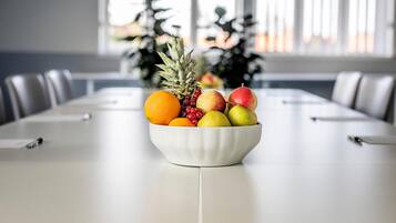 A conference table with a fruit bowl in the center, surrounded by chairs.
