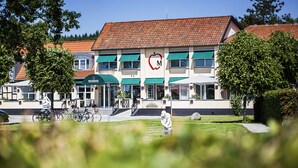 A building with a red-tiled roof, a green awning, and a white exterior. - Strandhotellet (Ebeltoft)