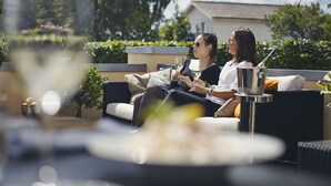 A couple sitting on a sofa with a glass of wine, a bottle, and a small table with a bowl and a plant. - Strandhotellet (Ebeltoft)