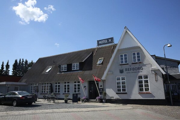A hotel named REFBORG with a traditional architectural style, featuring a prominent triangular roof and a signboard.