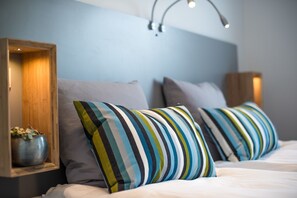 A bedroom with two beds, each with striped pillows and a wooden headboard.