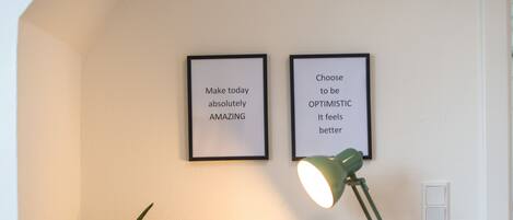 A desk with a lamp, a potted plant, and two motivational posters.