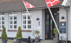 A building with a sign reading "REFBORG HOTEL SPISERI". There are two potted plants in front of the entrance.
