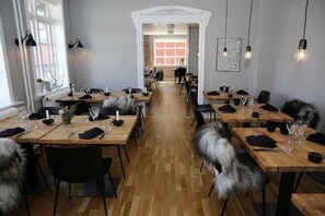 A restaurant with multiple wooden tables and black chairs, arranged in a spacious layout with a central walkway.