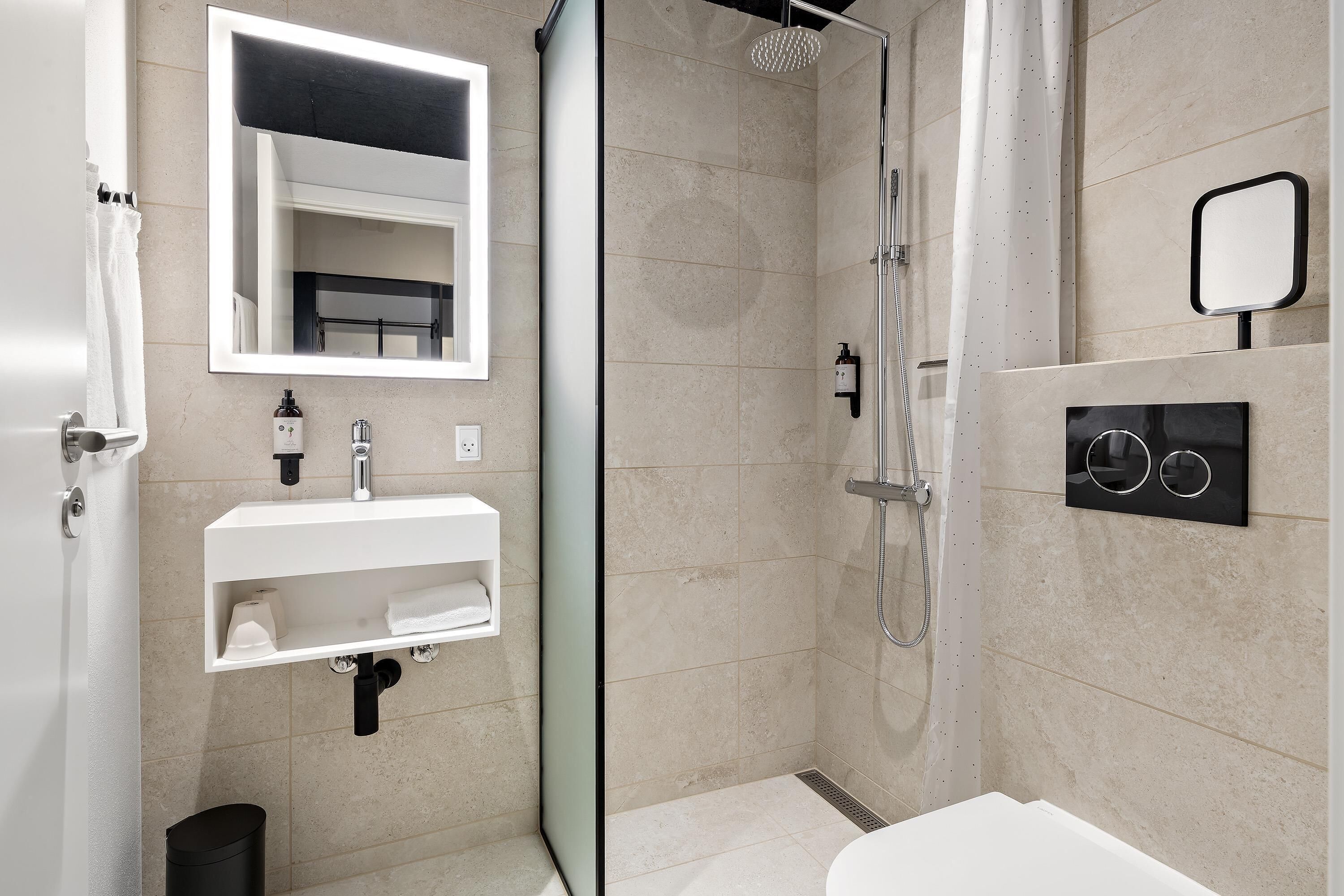 A modern bathroom with a glass-enclosed shower, a white sink, and a large mirror.