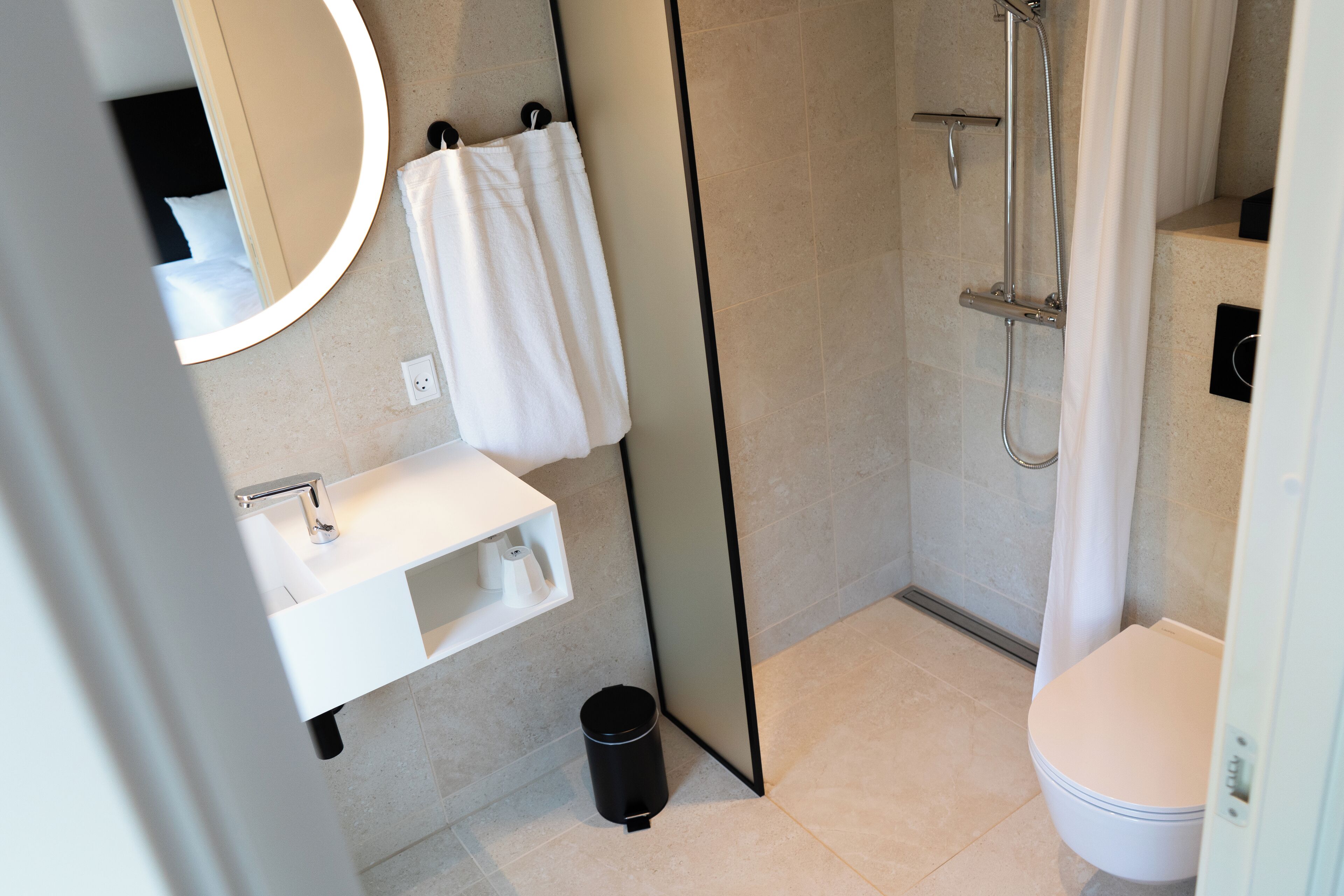 A modern bathroom with a white sink, mirror, and toilet.