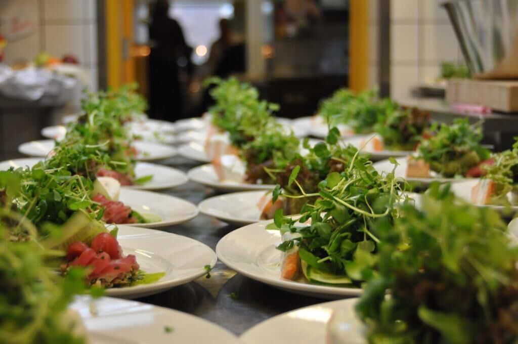 En buffet med forskellige retter, herunder salater og kød, anrettet på tallerkener.