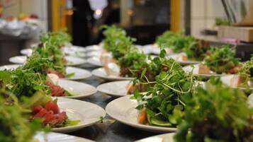 En buffet med forskellige retter, herunder salater og kød, anrettet på tallerkener.