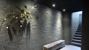 Un intérieur moderne avec un mur texturé, un banc en bois et un escalier.