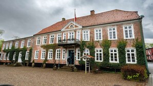 A traditional brick building with a tiled roof, multiple windows, and a small balcony. - Gram Slotskro (Gram)