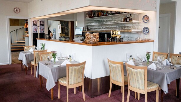 A restaurant with a bar area, multiple tables, and chairs. - Gram Slotskro (Gram)