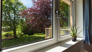 Una ventana con vista a un jardín y una barandilla metálica.