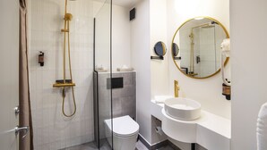 Een moderne badkamer met een douchecabine van glas, een toilet, een wastafel en een spiegel.