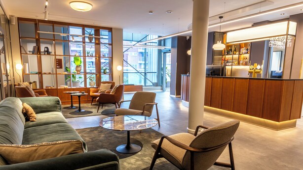 Een moderne lounge met zitplaatsen, een bar en grote ramen met uitzicht op de stad.