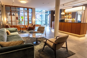 A modern lounge area with seating, a bar, and large windows offering views of the city.