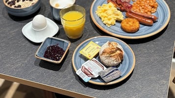 A breakfast table with various dishes including eggs, bacon, sausages, and fresh vegetables.