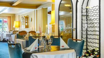 A dining area with round tables, blue upholstered chairs, and a wine rack.