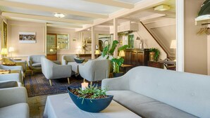 Amplia sala de estar con sofá, sillones, una mesa de centro con una planta y un comedor al fondo.