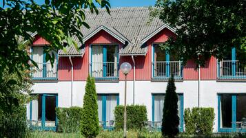 Un bâtiment rouge et blanc, doté de nombreuses fenêtres et de balcons, et entouré de verdure.