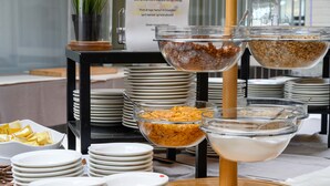 Una mesa con diferentes alimentos dispuestos en recipientes y platos transparentes, en formato bufé.