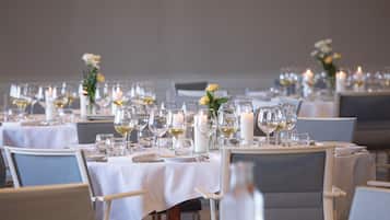 Ein Restaurant mit runden Tischen, gedeckt mit weißen Tischdecken, Kerzen und Weingläsern.