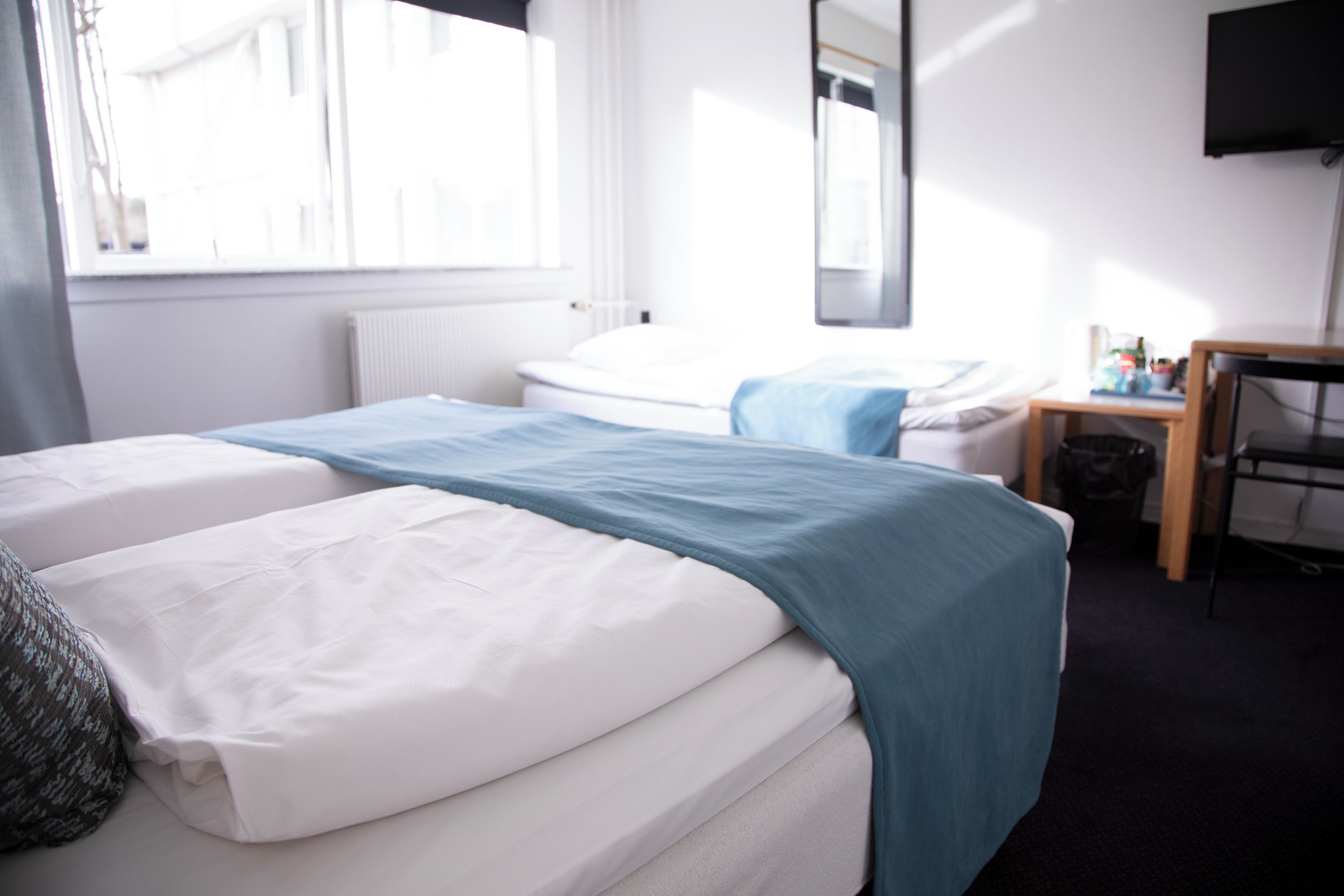 Una habitación de hotel con dos camas, un escritorio, una silla y un televisor.