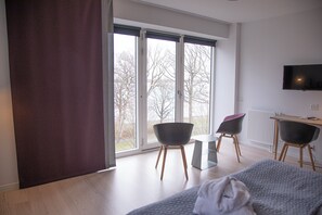 A modern hotel room with a large window, a bed, a desk, and two chairs. - Hotel Strandparken (Holbaek)