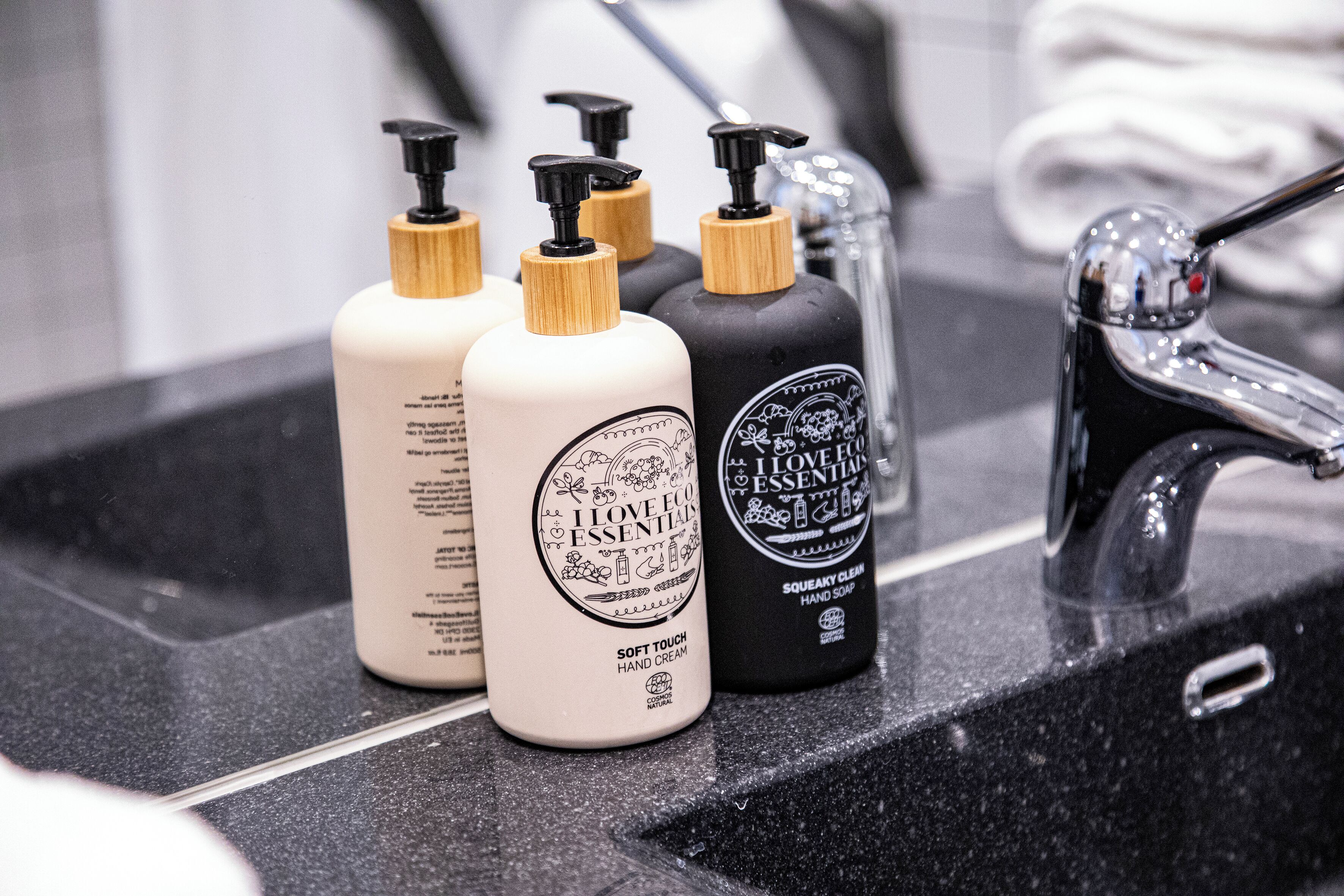 Three bottles of hand cream on a black countertop.