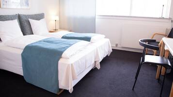 A hotel room with two beds, a desk, and a chair.