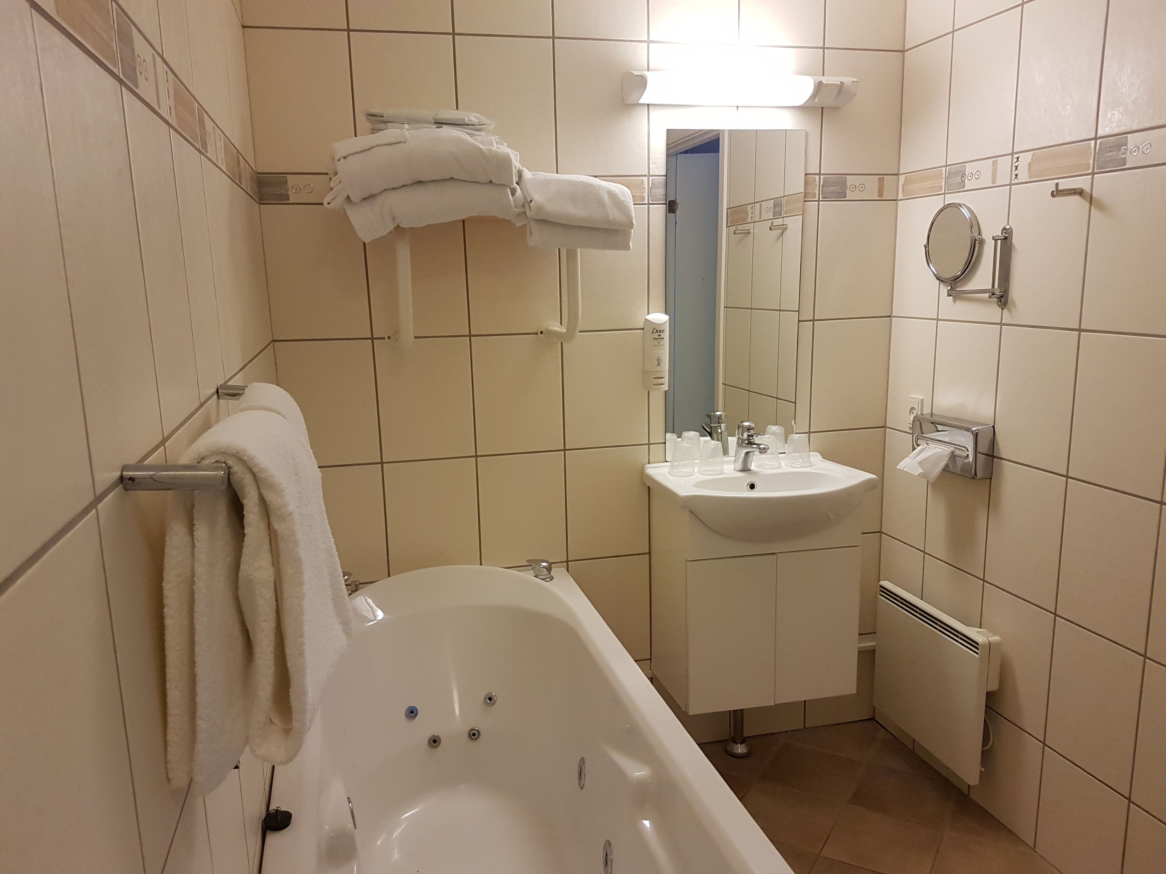 A bathroom with a bathtub, a sink, a mirror, and a towel rack.